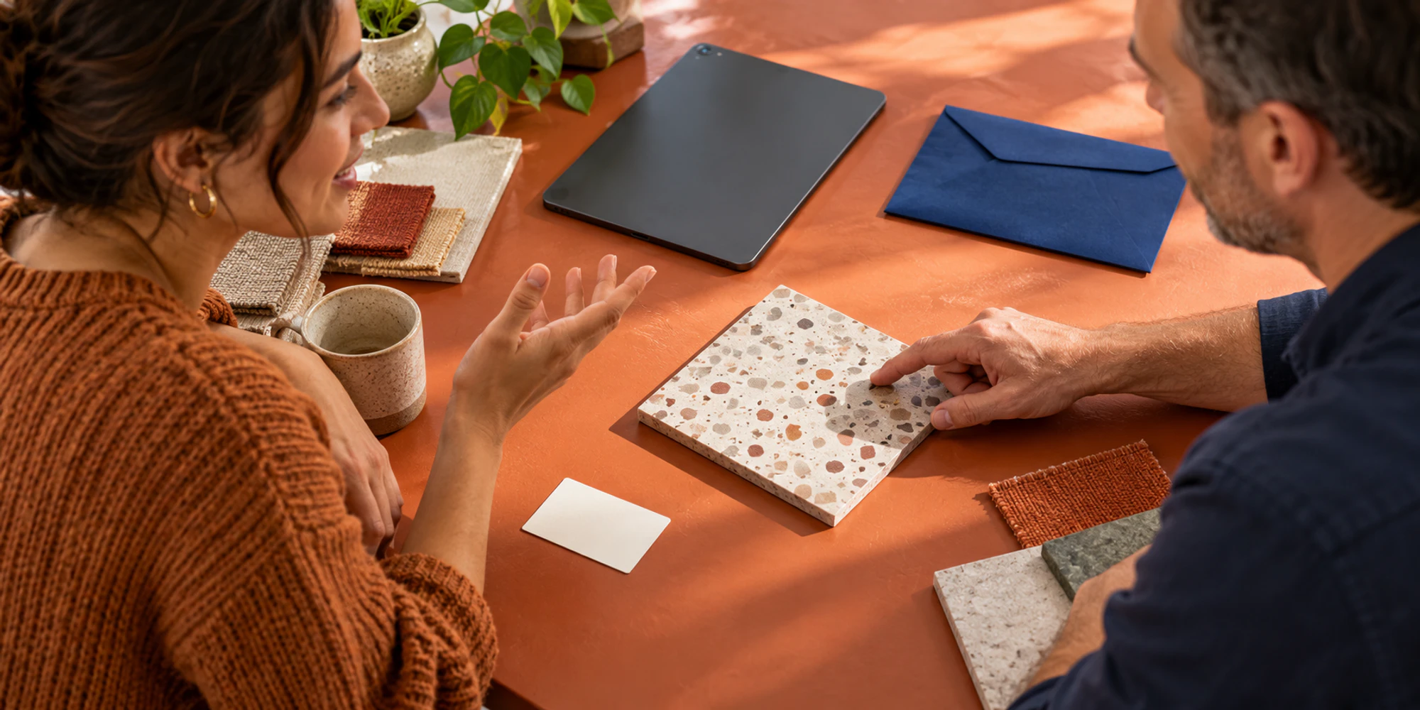 An adult learner and course adviser discuss practical course materials while an application envelope remains closed