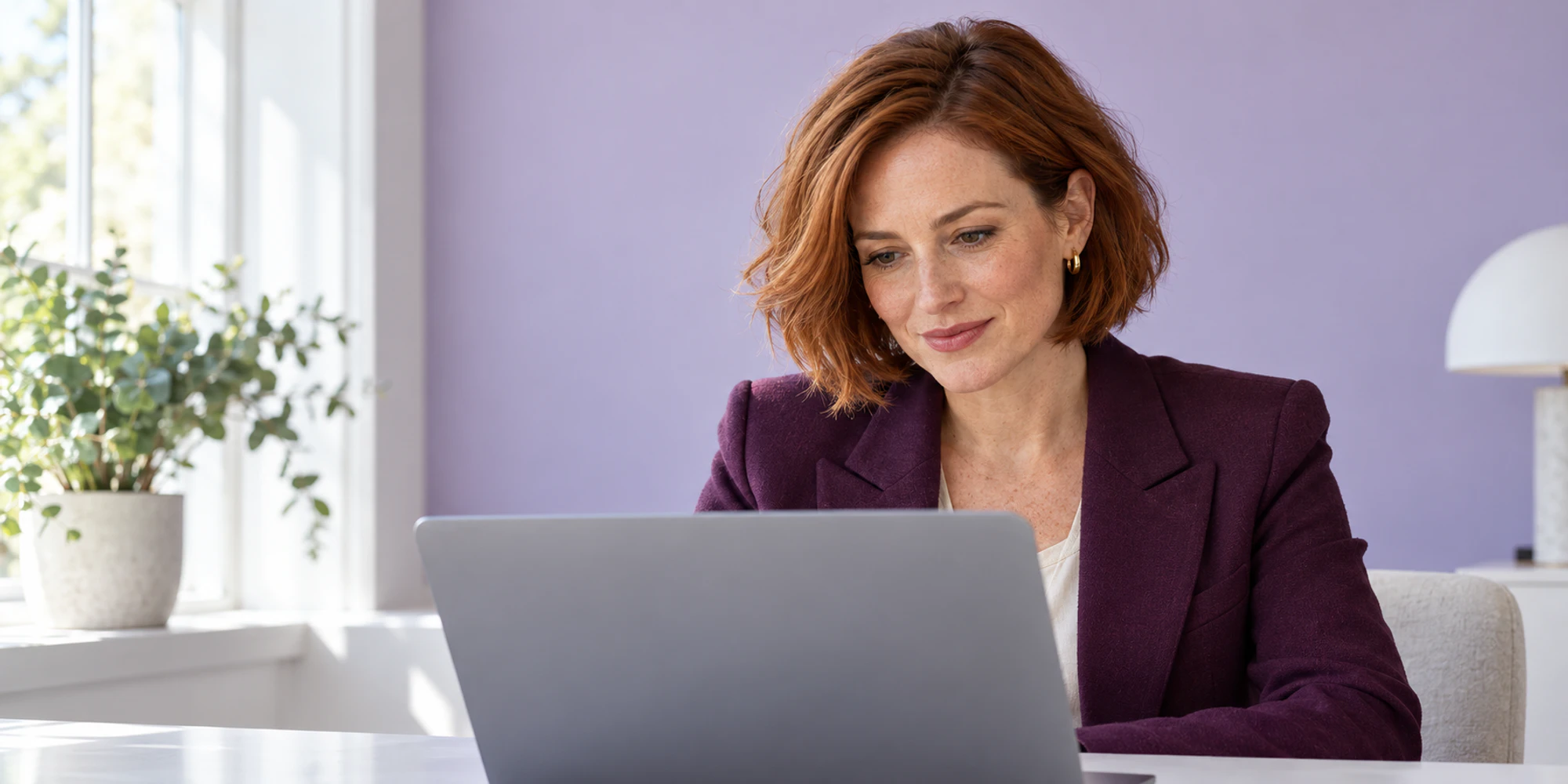 Illustrative support lead reviewing a laptop beside a lilac wall